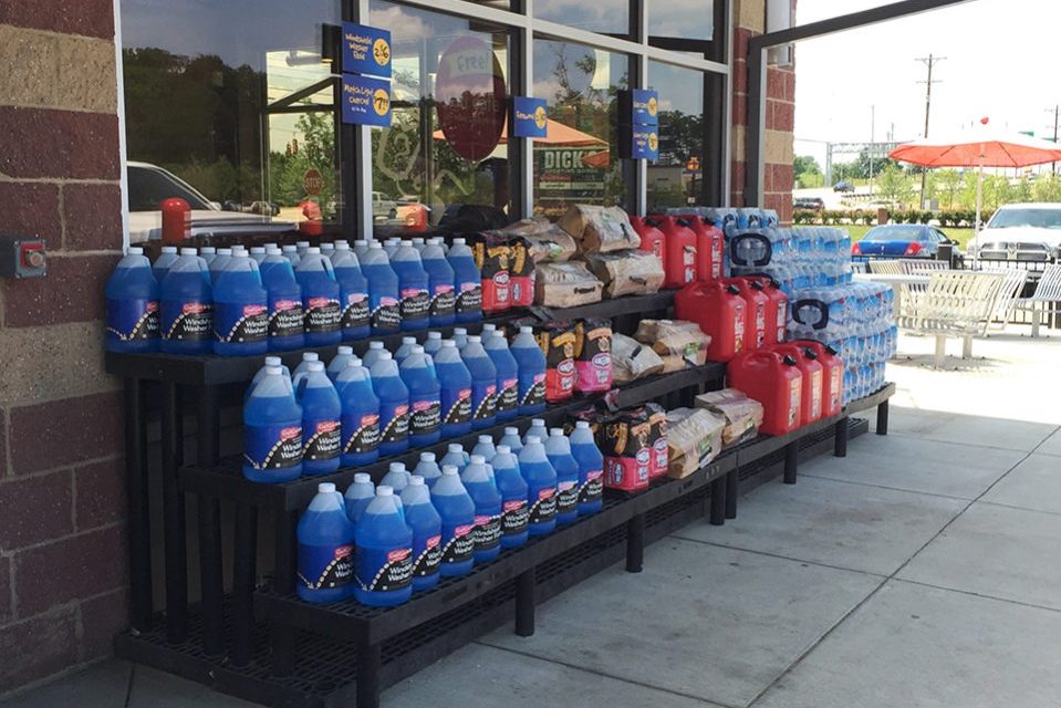 a three-tier plastic display holding heavy items like antifreeze and charcoal